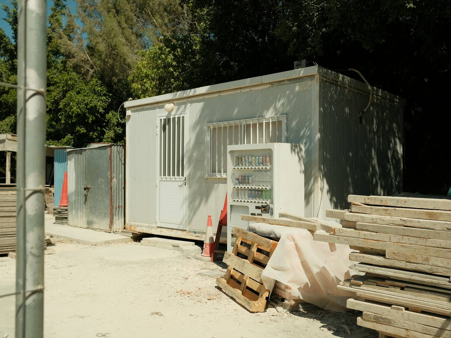Bâtiment modulaire blanc posé sur un site, avec des matériaux de construction à côté.