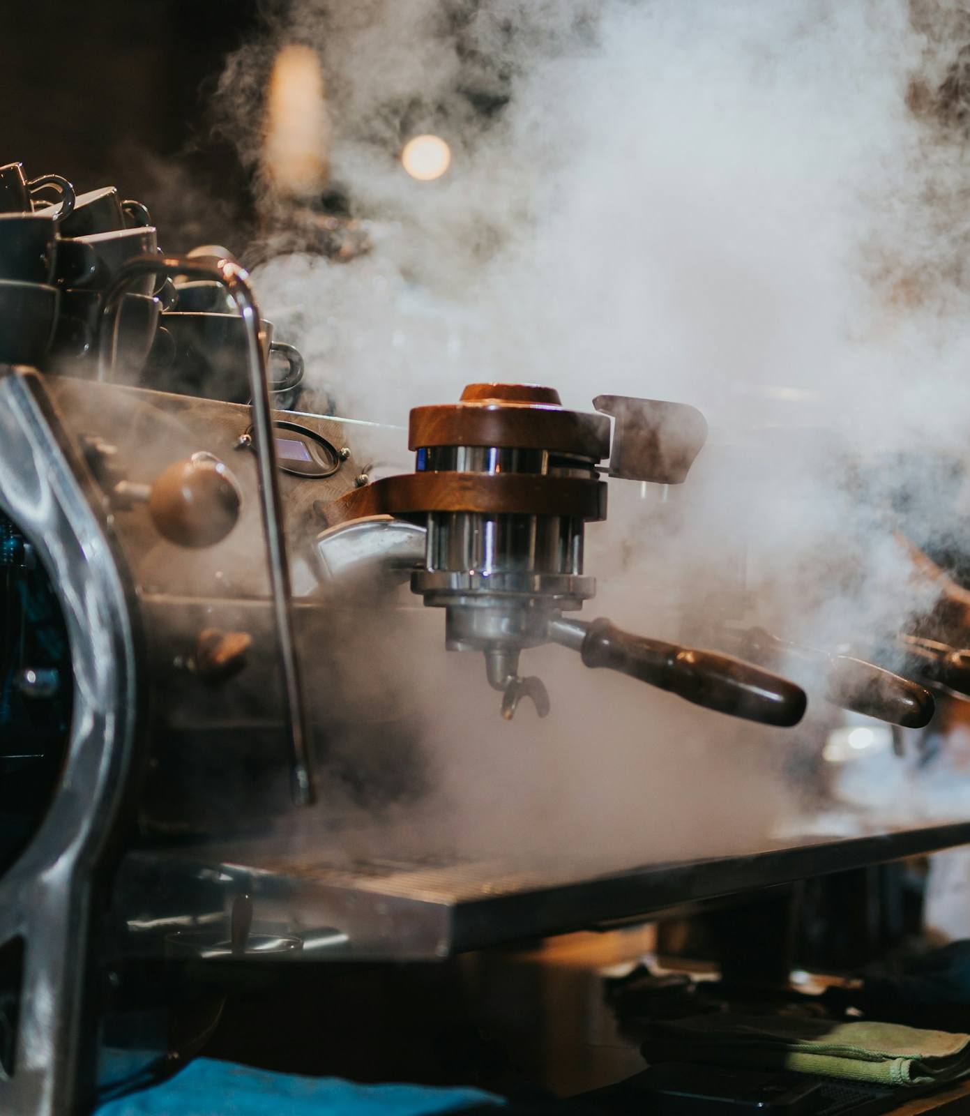 Machine à café professionnelle noire et argentée dégageant de la vapeur.