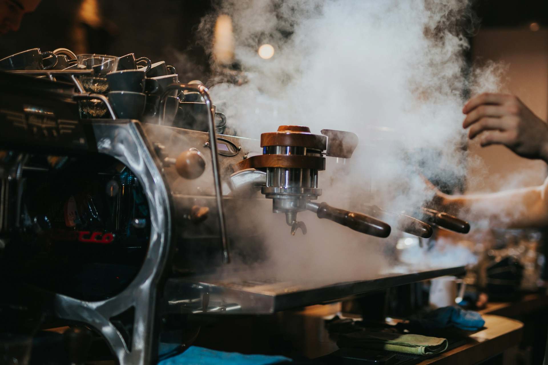 Machine à café professionnelle noire et argentée dégageant de la vapeur.