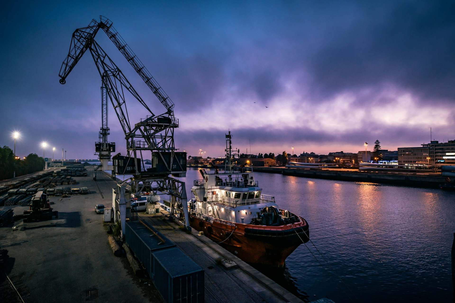 Grue portuaire et navire à quai au crépuscule.