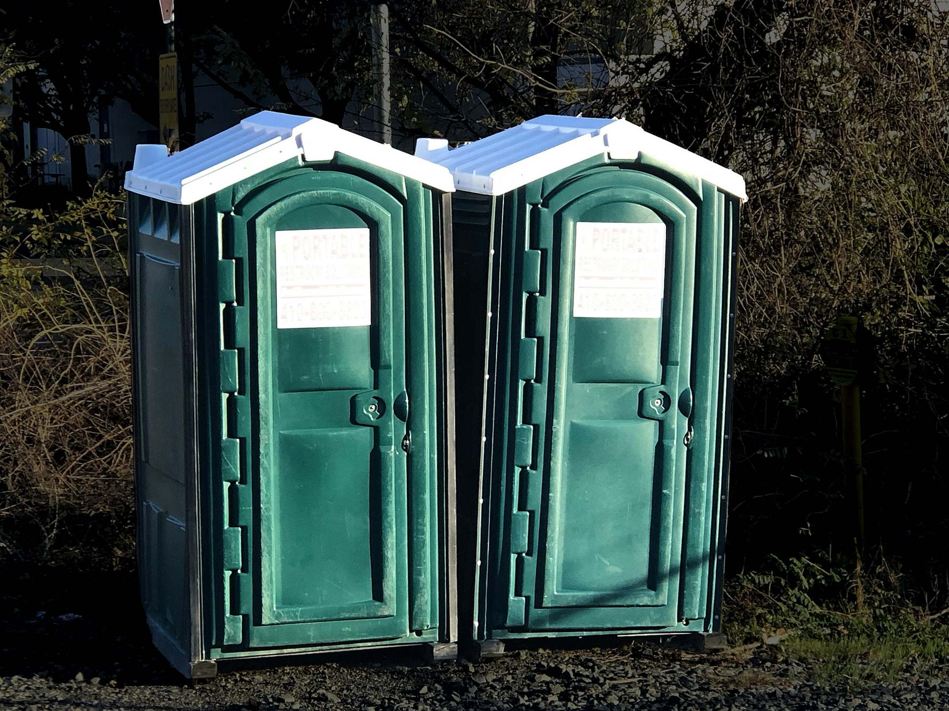 Deux cabines sanitaires mobiles vertes côte à côte.